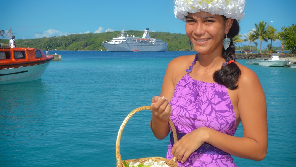 MS ASTOR vor Bora Bora mit junger Frau im Vordergrund.