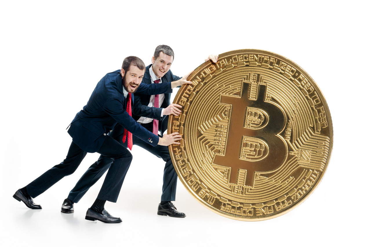 Zwei Männer rollen einen Bitcoin